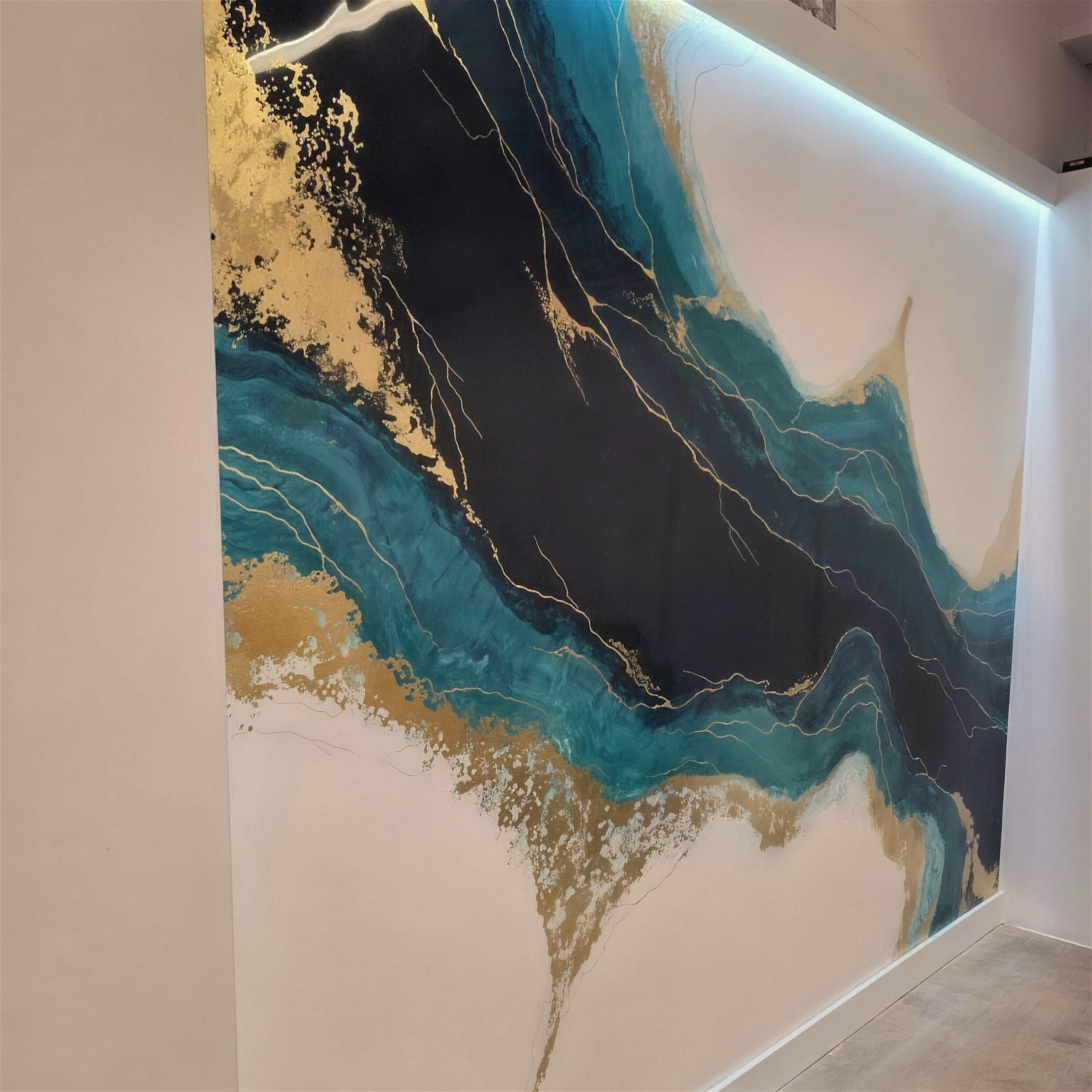 Large bespoke feature wall of flowing teal, black and gilded veining across white plaster, washed by a concealed LED cove above.