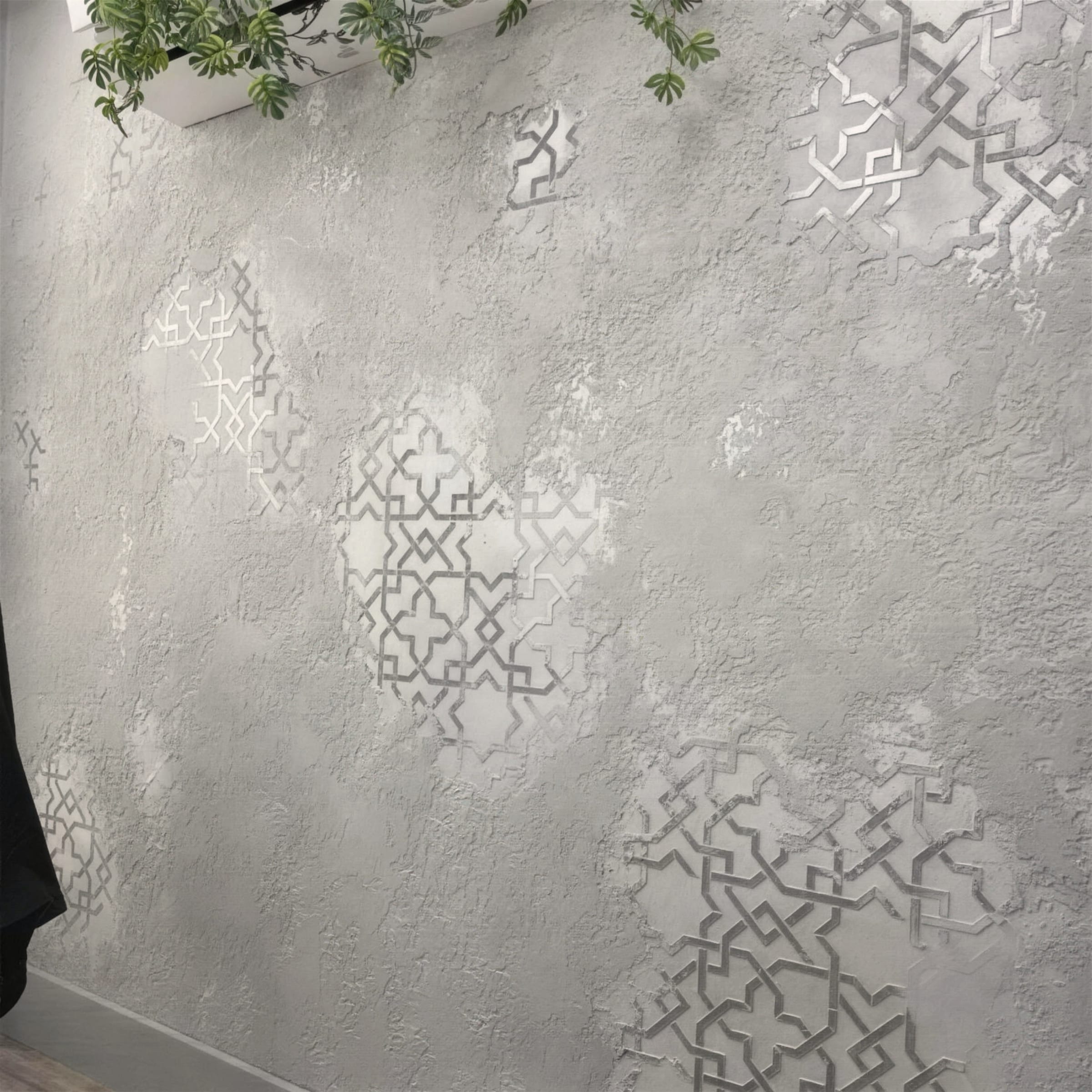 Sweeping angled view of a heavily textured plaster wall with scattered silver stencil medallions beneath a greenery planter.