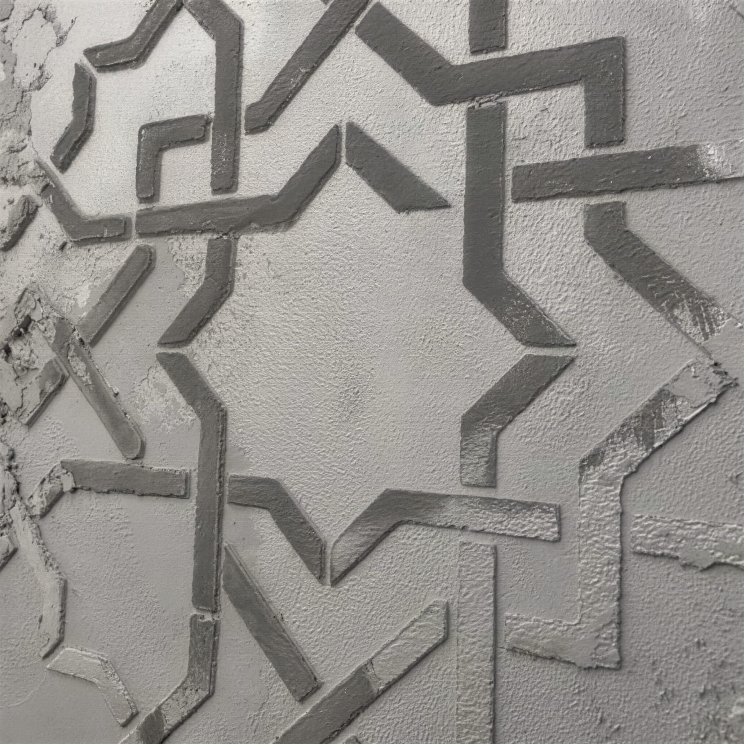 Crisp macro of an eight-point star stencil relief cut into grey textured plaster, edges sharply defined.